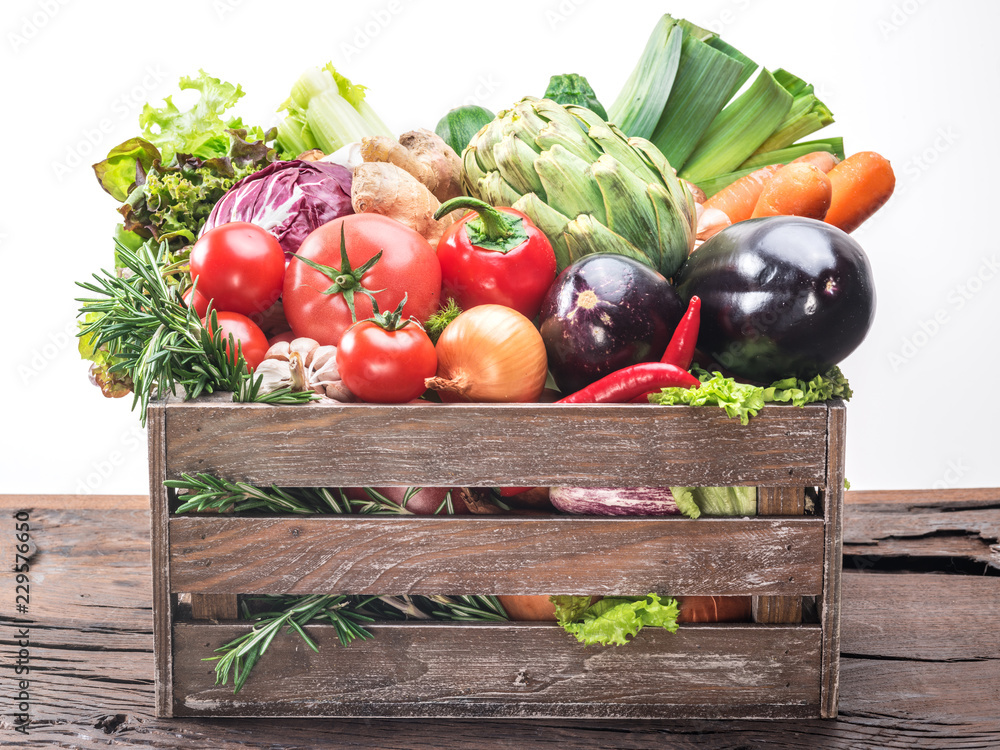 Fresh multi-colored vegetables in wooden crate.