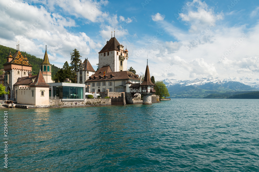 Beautiful little tower of Oberhofen castle in the Thun lake with mountains on background in Switzerl