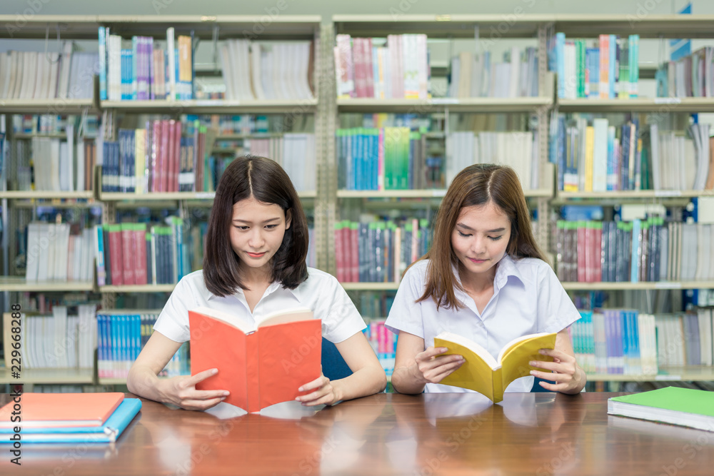 两名亚洲学生在大学图书馆一起学习。大学生。