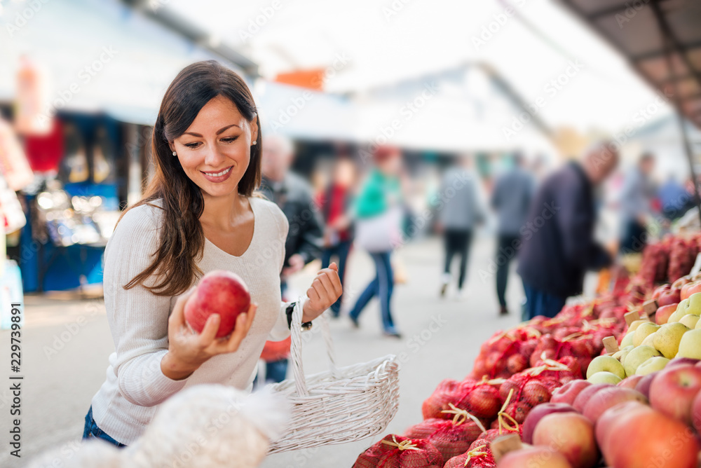 一个微笑的女人在户外食品市场购买的肖像。