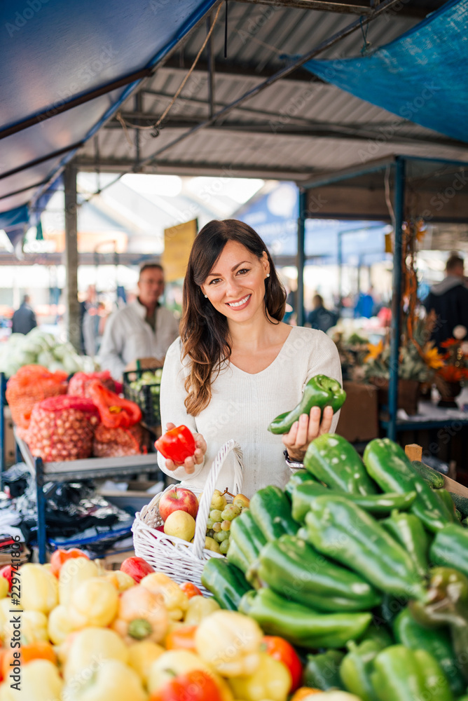 Beautiful casual woman buying groceries at local market.