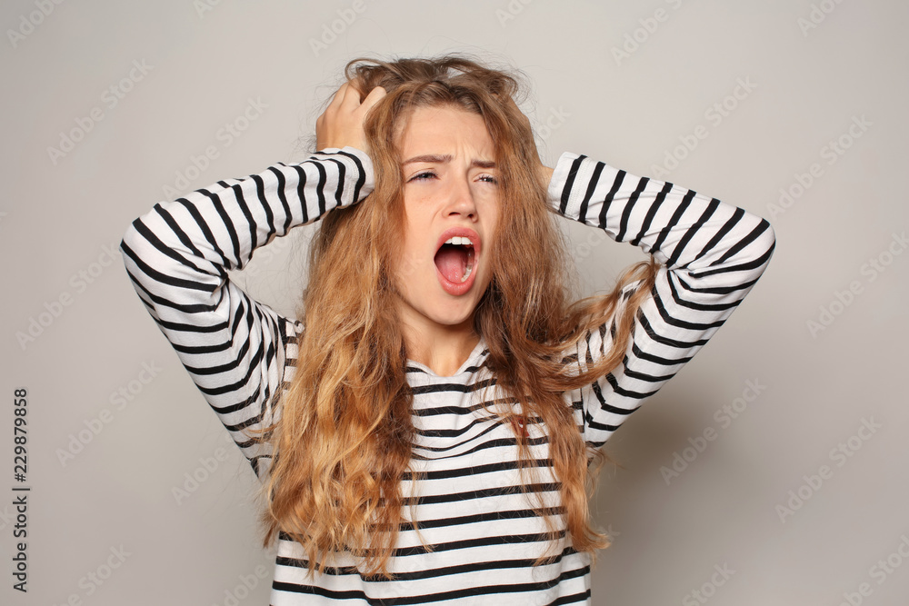 Portrait of beautiful young woman suffering from headache on light background