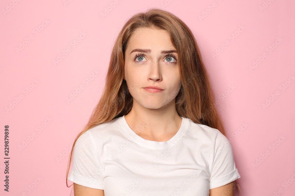 Portrait of thoughtful young woman on color background