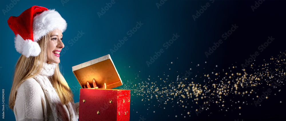 Happy young woman with Santa hat opening a gift box