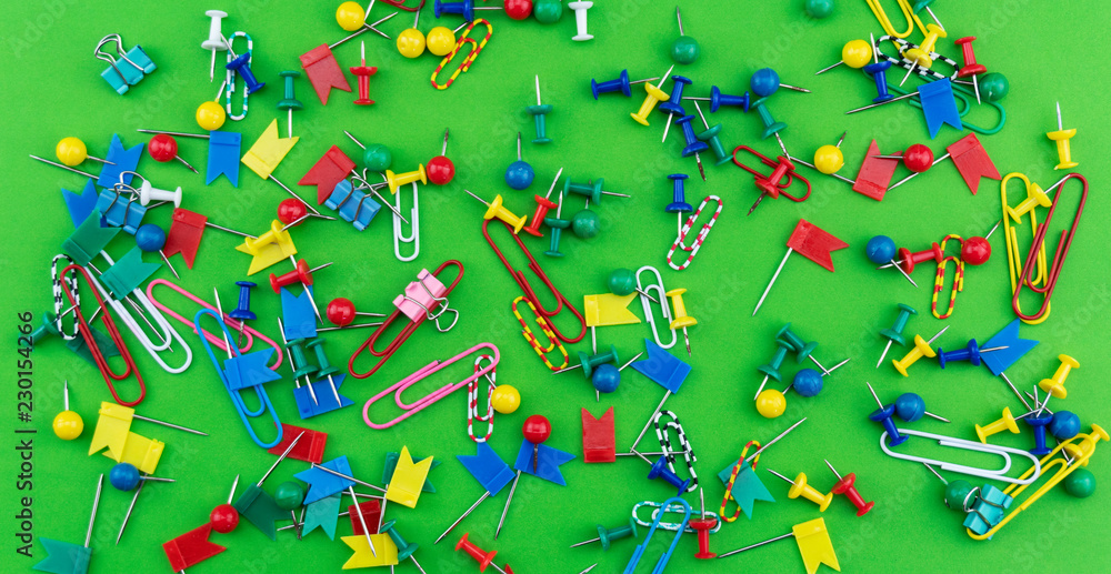 Set of colorful color push pins Thumbtacks top view isolated on green background.