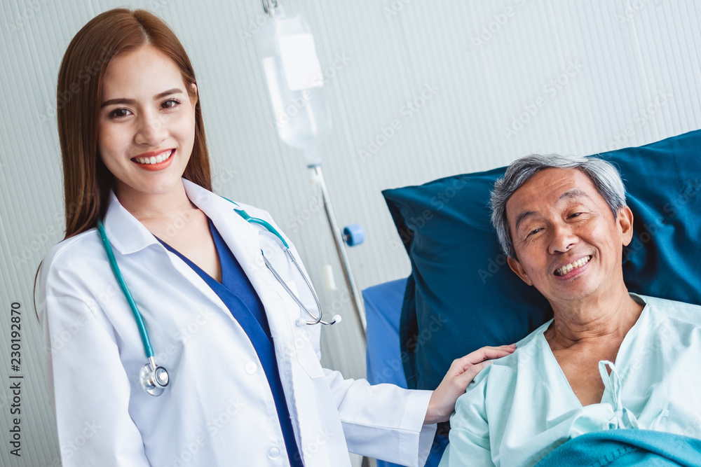 Asian doctor woman and nurse encourage disabled old man patient sitting on wheelchair at hospital, a