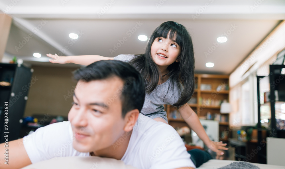 快乐的小女孩女儿和爸爸一起玩，骑爸爸回来，爸爸躺在家里的床上