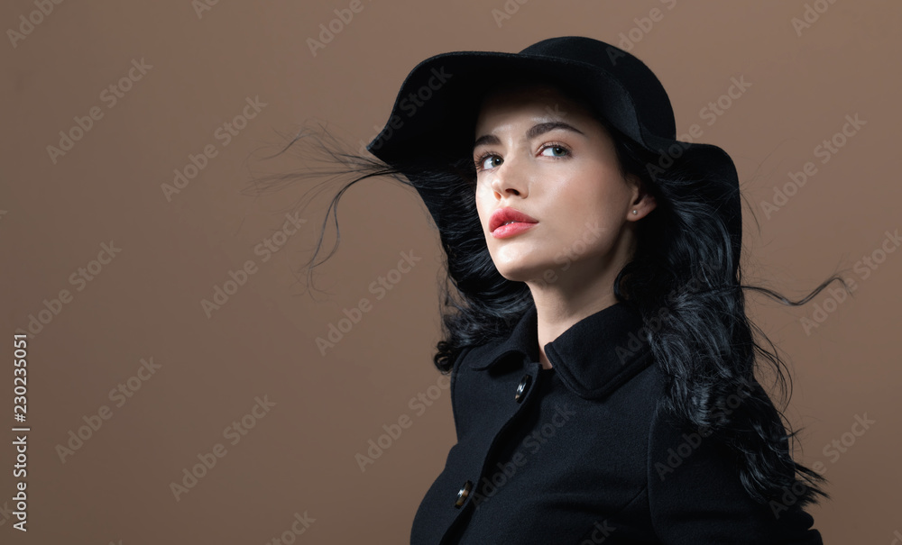 Beautiful young woman in a fashionable coat on a brown background