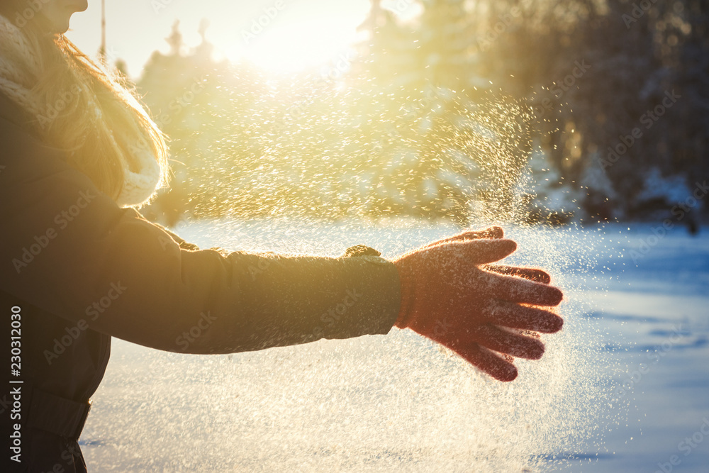 戴着红手套的女性双手在雪地里拍手。冬季概念。阳光明媚