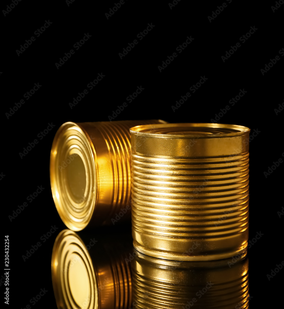 Golden tin cans on black background