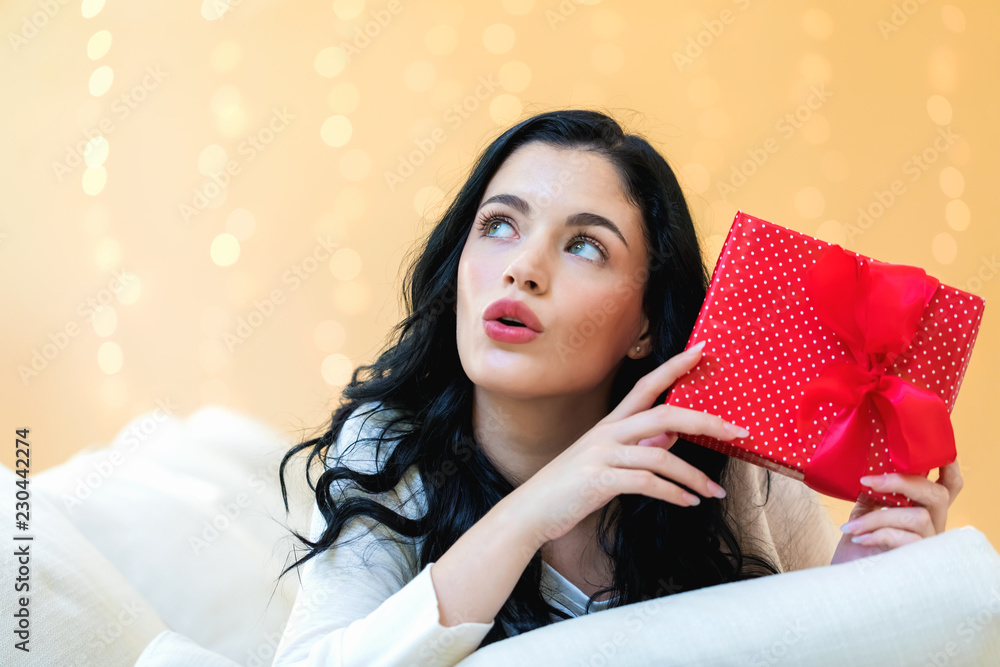 Young woman holding a gift box in her home