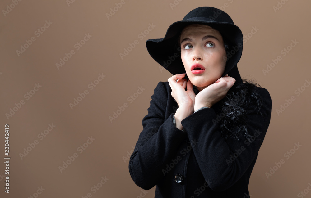 Beautiful young woman in a fashionable coat on a brown background