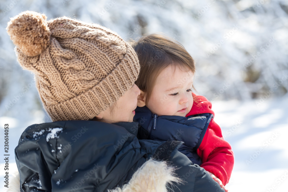 蹒跚学步的男孩和妈妈在雪地里玩耍