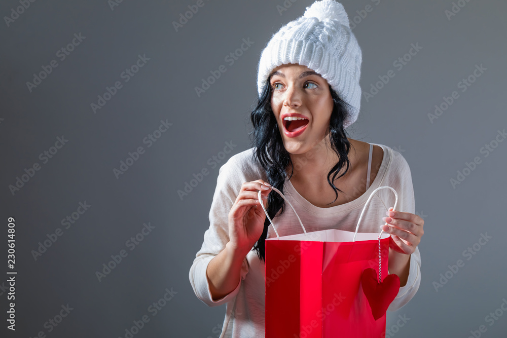 Happy young woman holding a shopping bag on a gray background