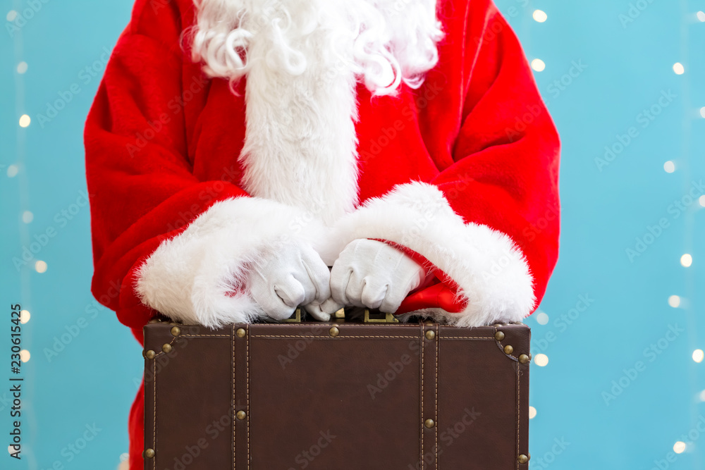 Santa holding a suitcase on a shiny light blue background