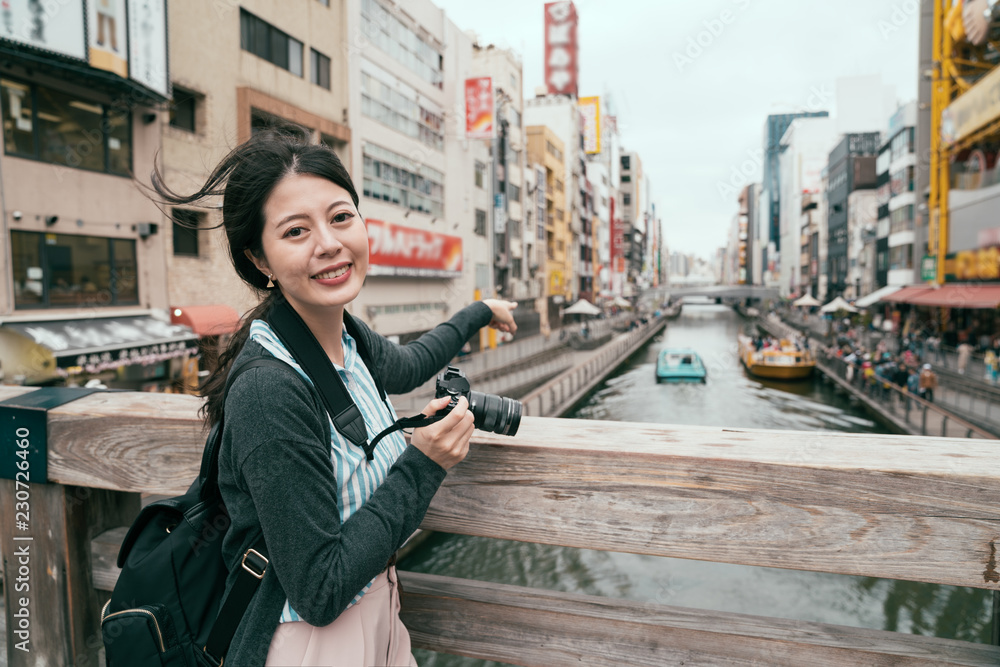 亚洲女孩指着运河上的船