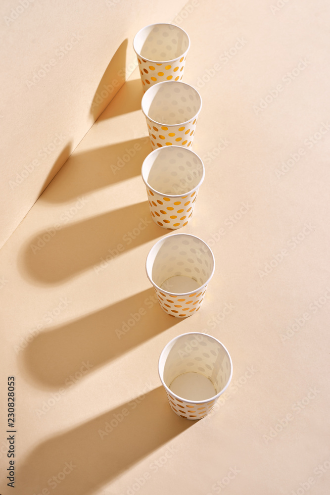 Golden polka dot paper cup isolated on beige background