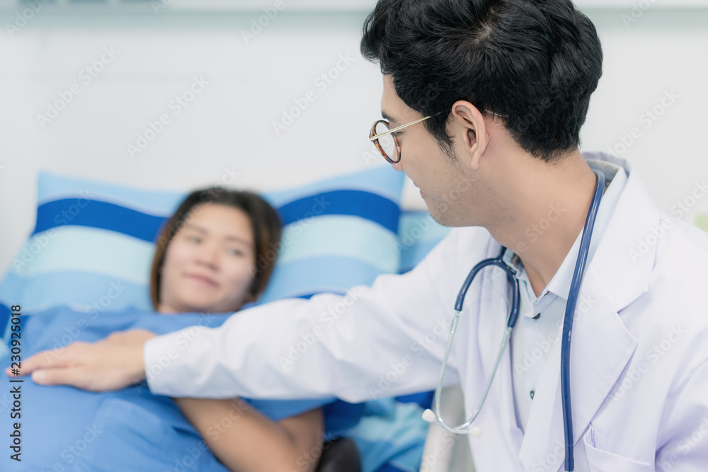 Asian young pregnant woman lying down talking and visit to her doctor man in a room.