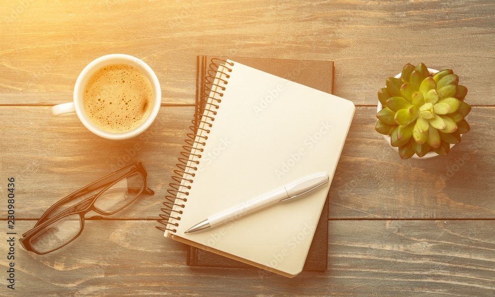 Notebooks and cup of strong coffee on wooden background.