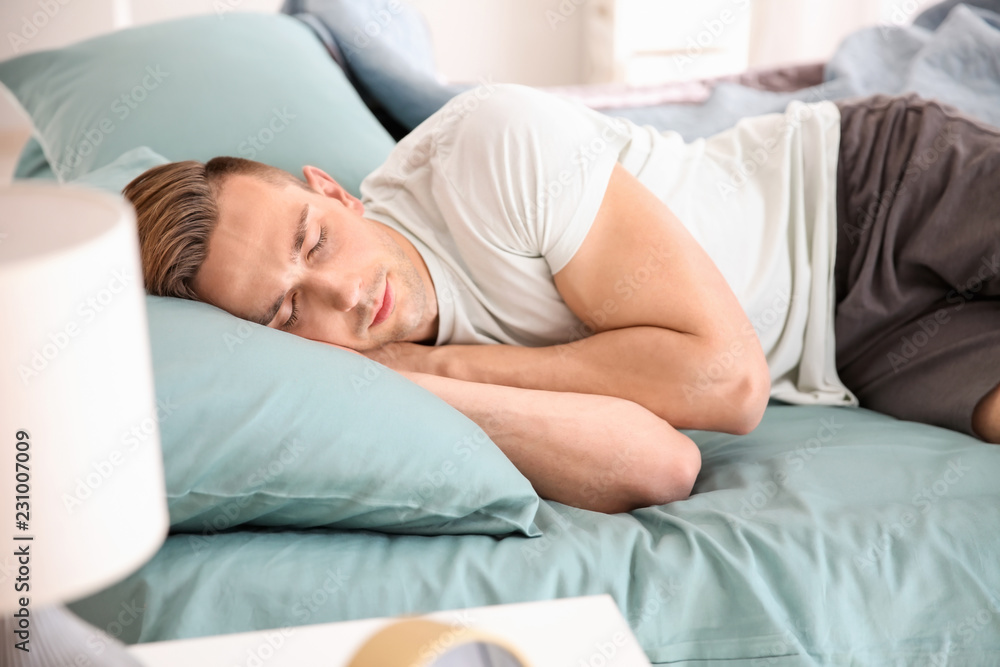 Handsome man sleeping in bed at home