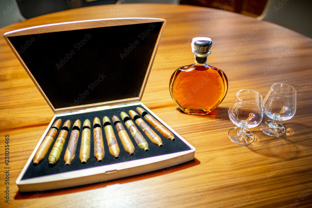 Close-up of luxury cigar set with cognac on the wooden table indoors