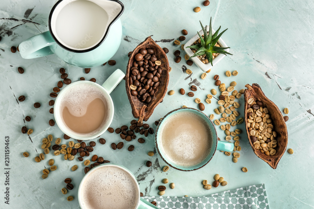 Cups of tasty aromatic coffee with jug of milk and beans on light table