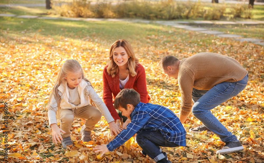 Happy family playing with leaves in autumn park