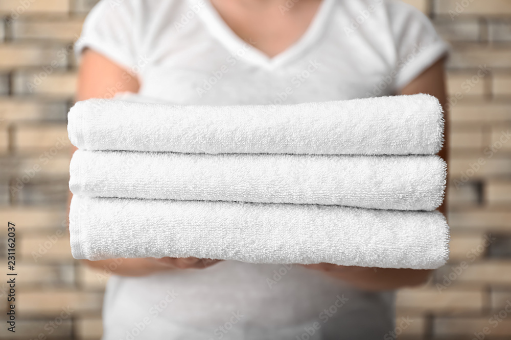 Woman with stack of clean towels, closeup