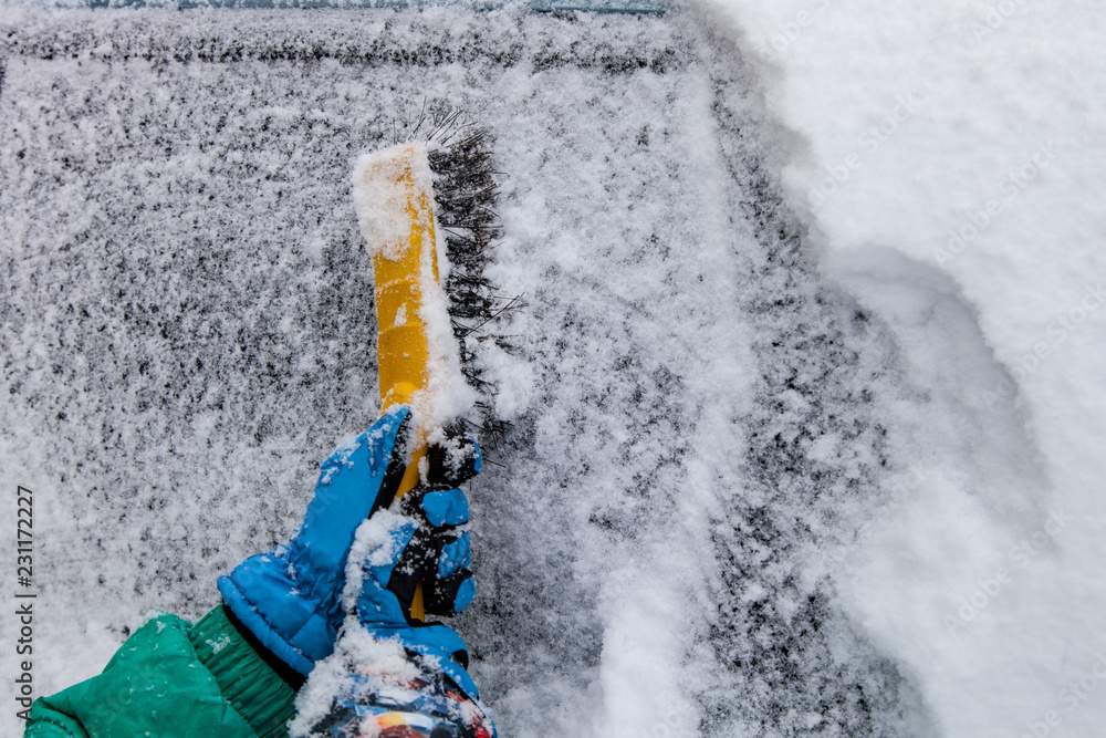 Cleaning snow from car with brush