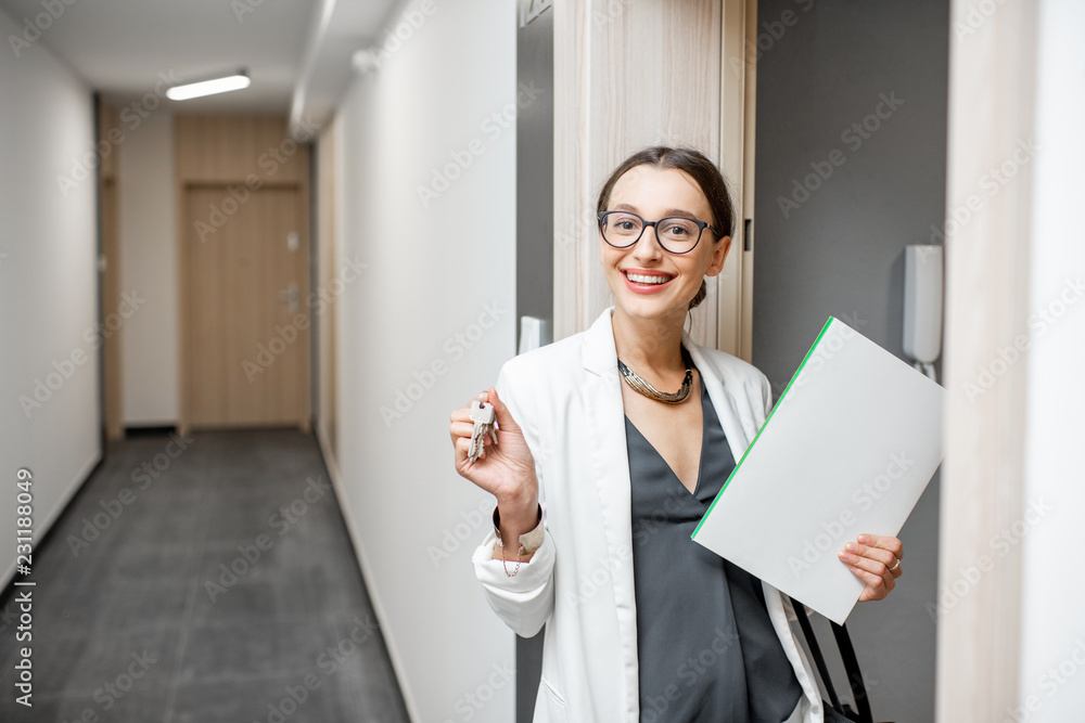 一个激动的女人拿着钥匙和文件站在新公寓门口的肖像