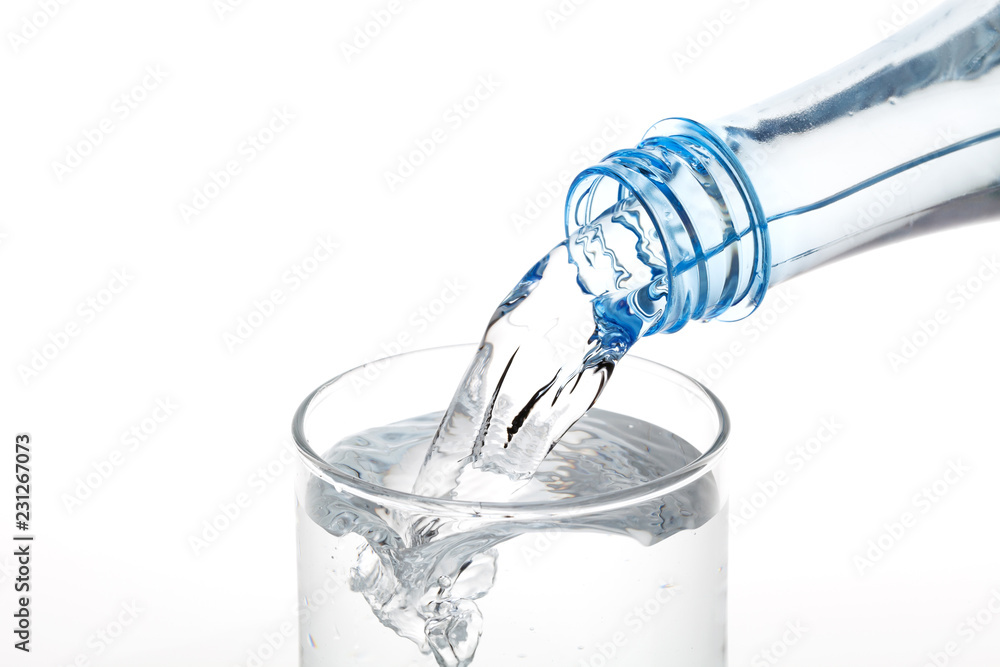 Pouring water from bottle into glass on white background.