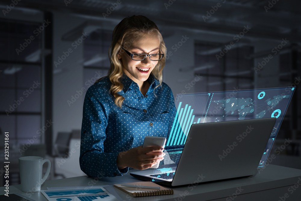 Beautiful blonde working on laptop and infographs out of screen. Mixed media