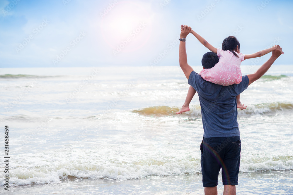 Daughter riding father neck on the beach.Family concept