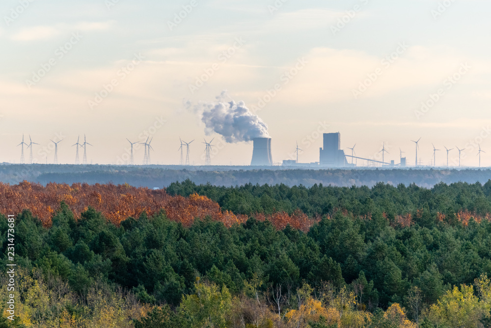 Kohlekraftwerk umgeben von Windrädern