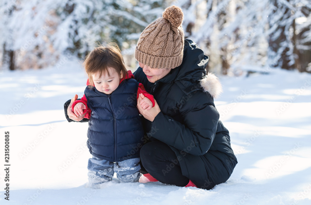 蹒跚学步的男孩和妈妈在雪地里玩耍