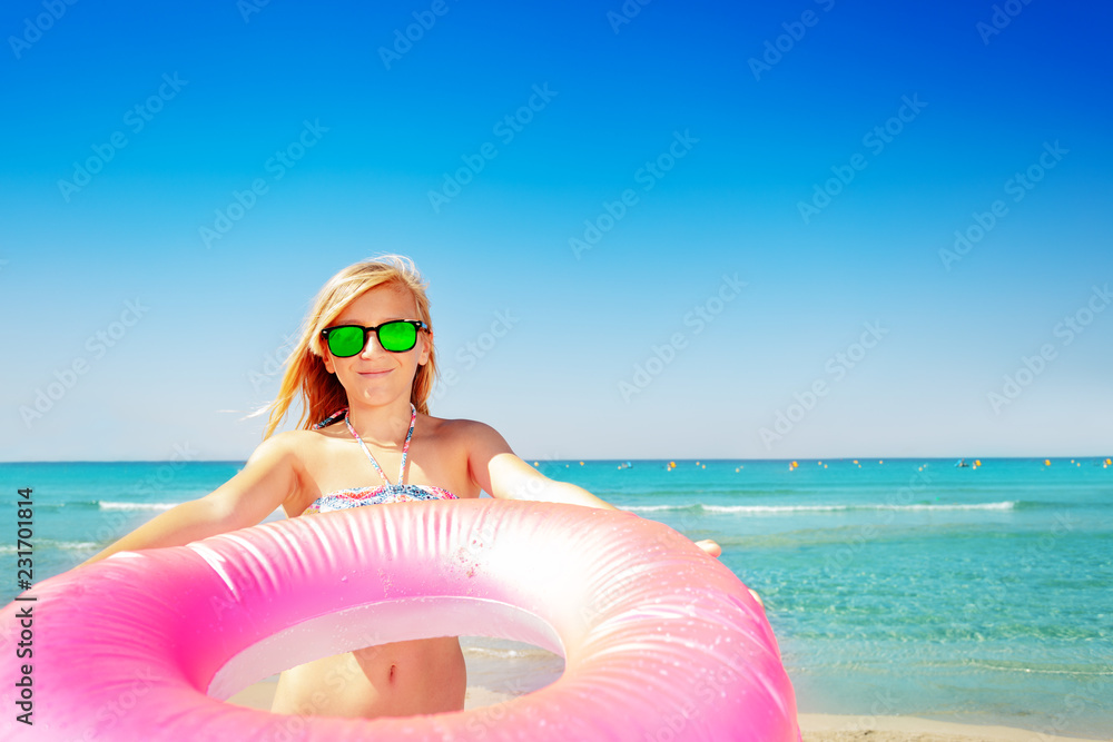 Smiling girl with pink swim ring on the beach