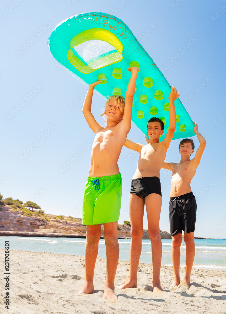 Happy boys with big air mattress above their heads