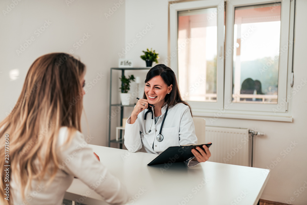 Beautiful doctor and young patient talking in the doctorss office.