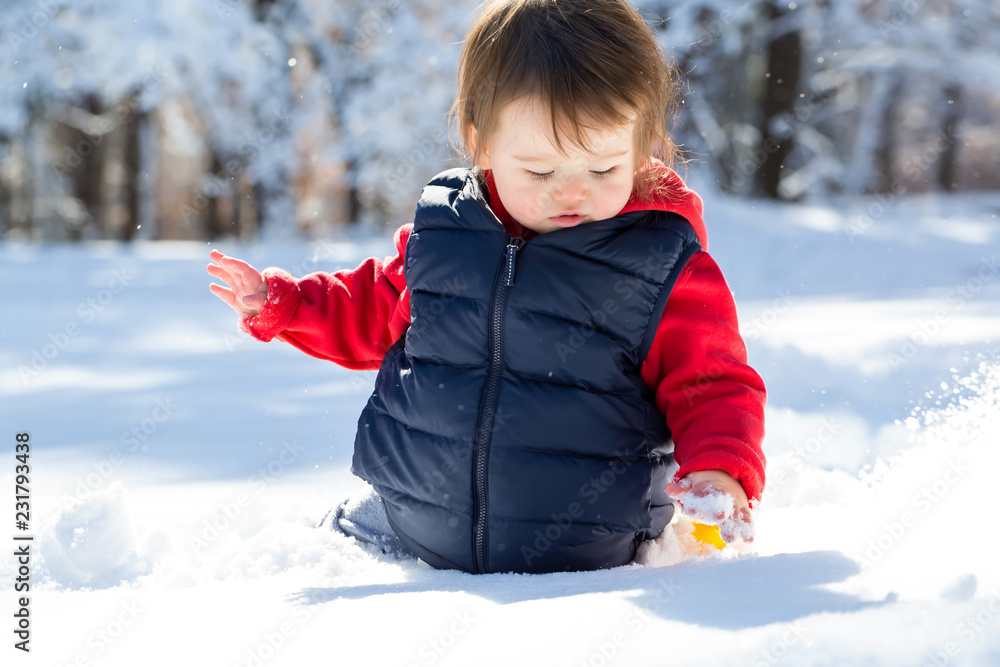 冬日里，一个蹒跚学步的男孩在雪地里玩耍