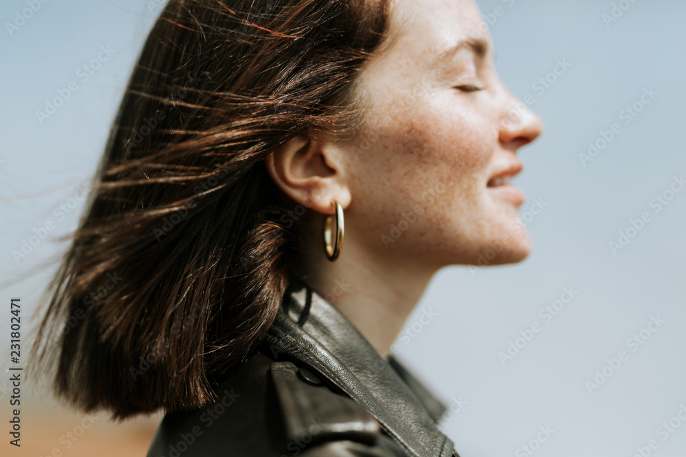 Side view of  a woman in leather jacket standing in a park