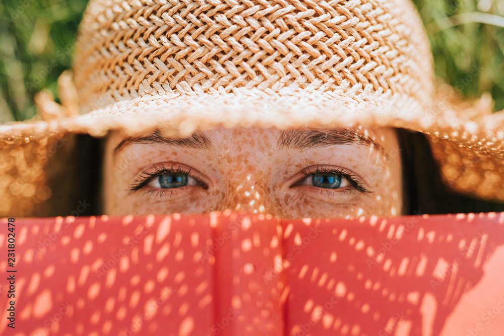 一个女人用一本红书遮住脸的特写