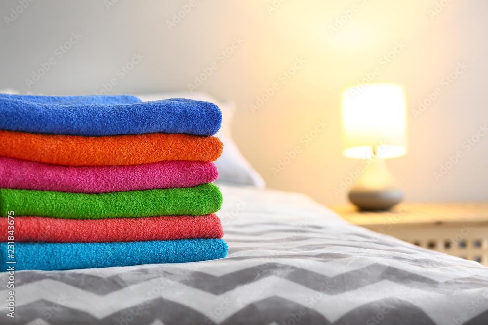 Stack of clean terry towels on bed