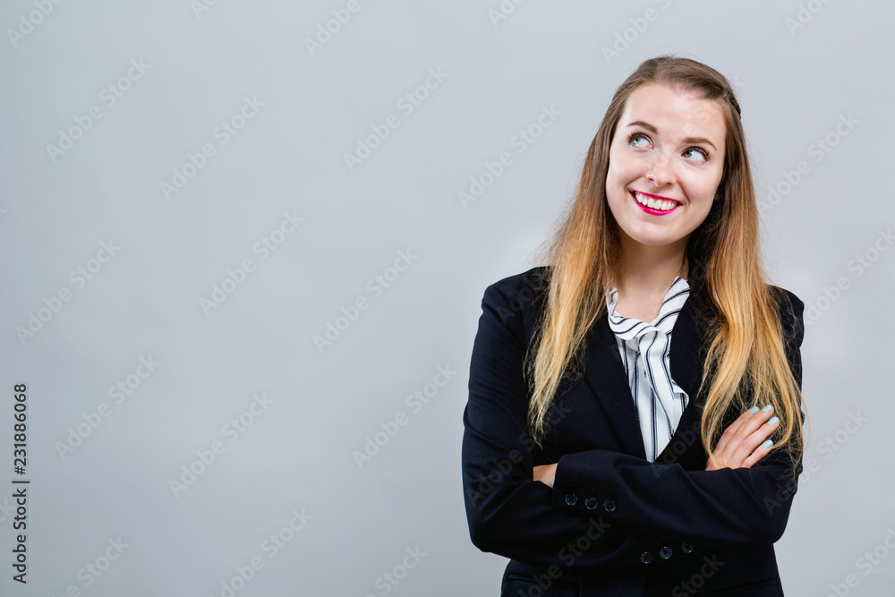 灰色背景下，年轻女子摆出若有所思的姿势