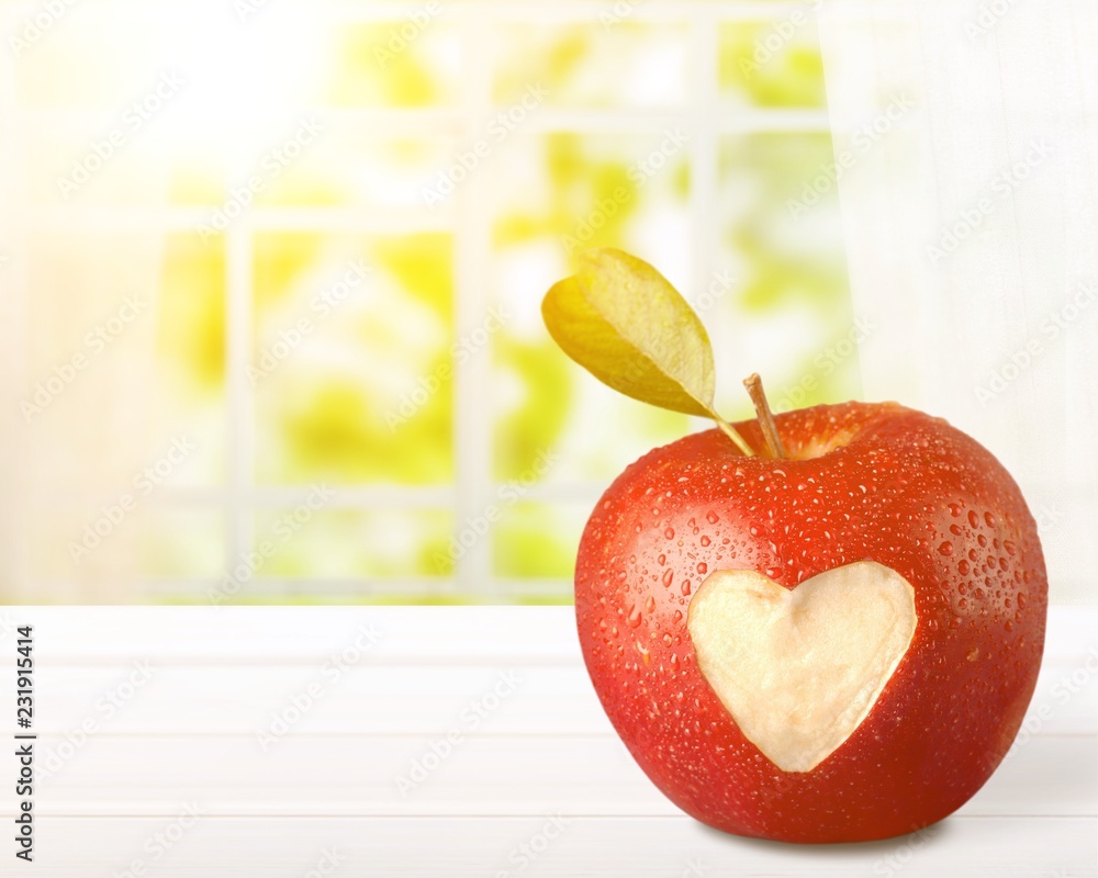 Red apple with a heart shaped cut-out on backgrouund