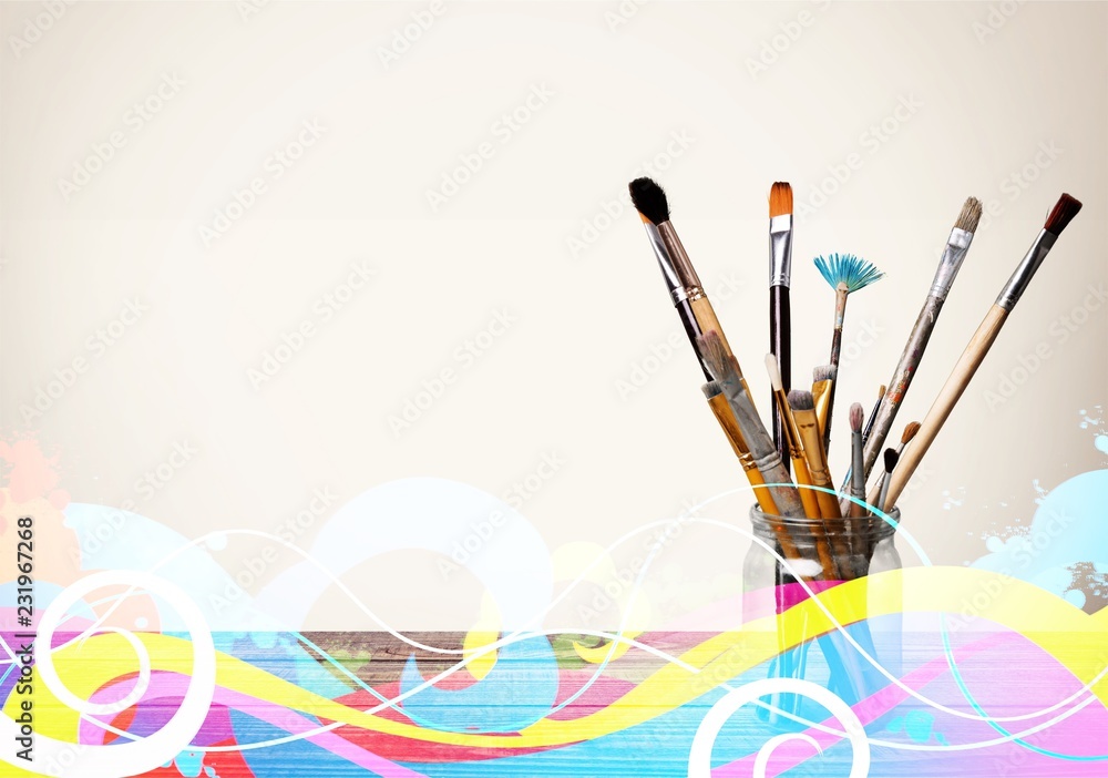 Brushes in a glass jar on the table and white wall