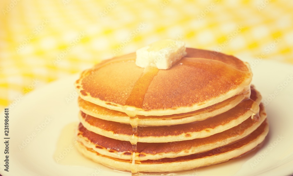 Stack of Small pancakes in syrup on background