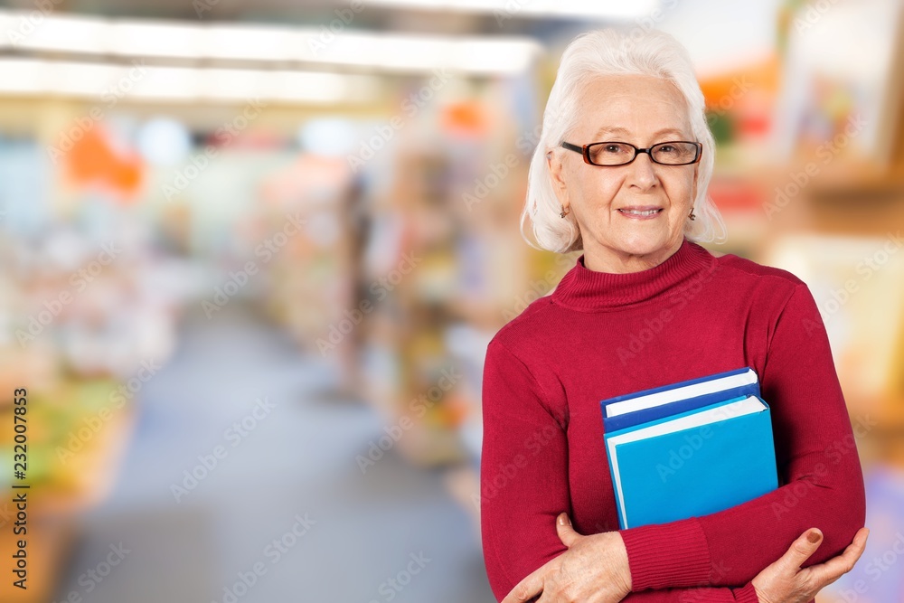 Mature woman teacher with books on background