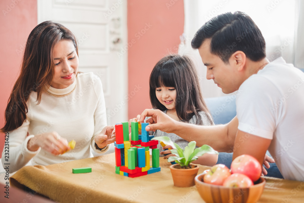 Girl daughter playing blocks toy over father and mother, happy family concept