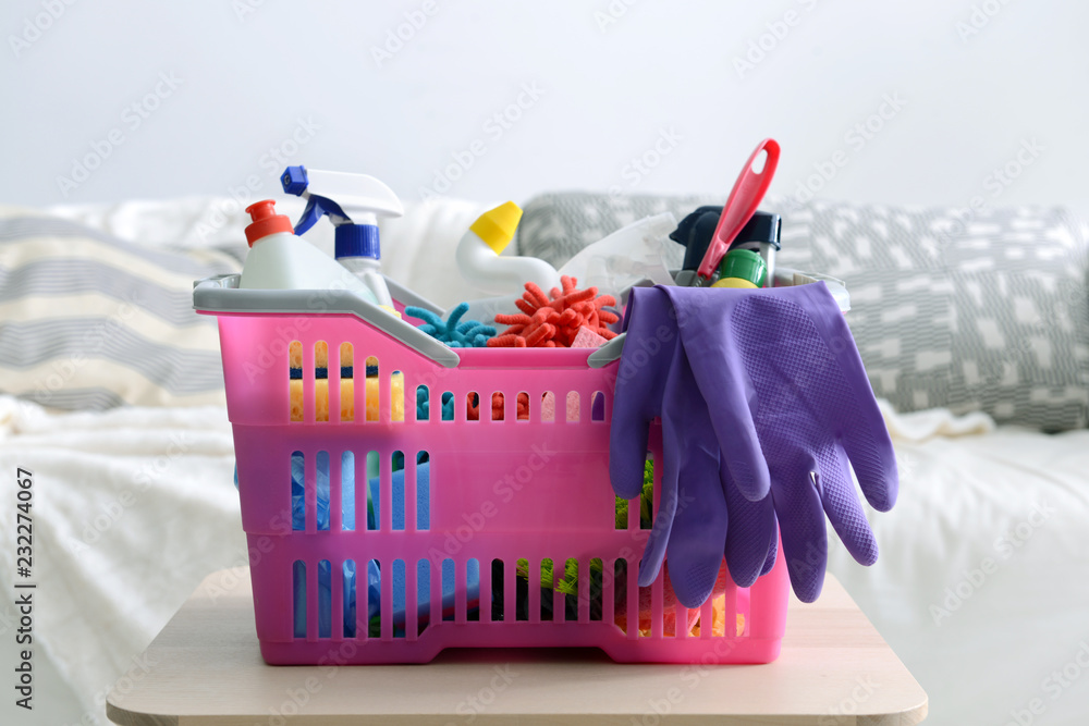 Basket with cleaning supplies on stool indoors