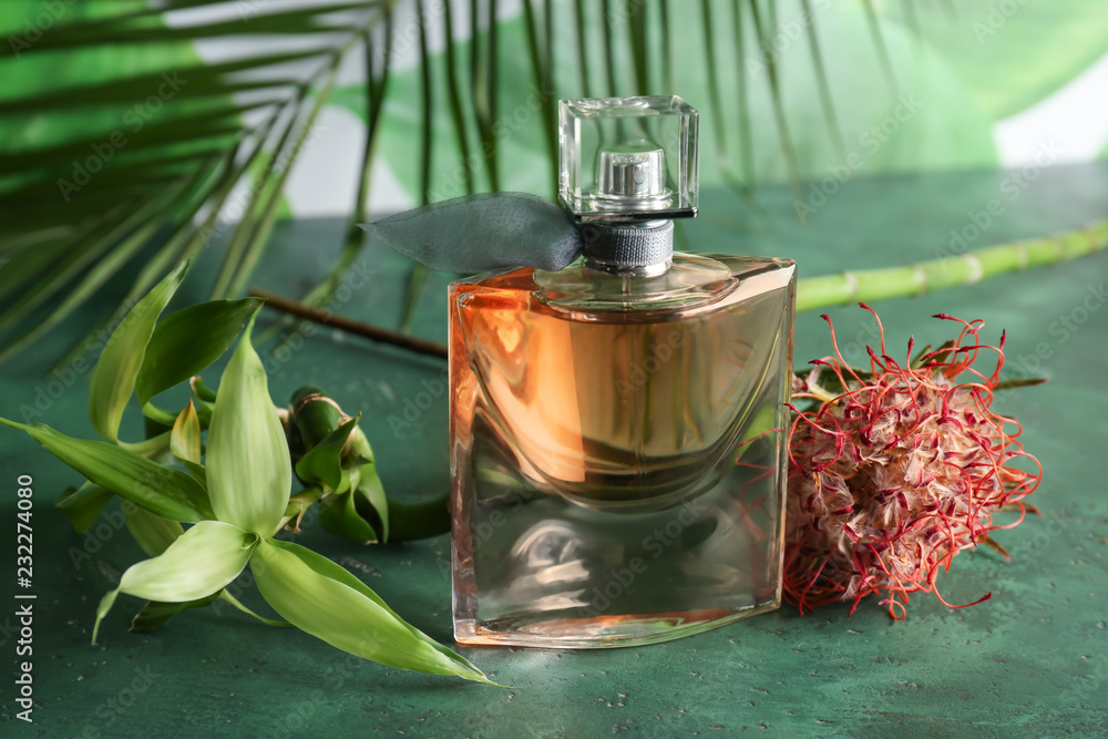 Bottle of perfume and flower on color table